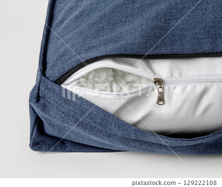 Close-up of open zipper on blue cushion revealing white filling 129222108