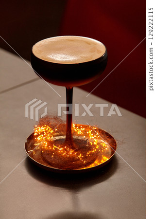 Espresso martini cocktail glass standing on a copper plate with sparkling christmas lights Espresso martini cocktail glass standing on a copper plate with sparkling christmas lights 129222115