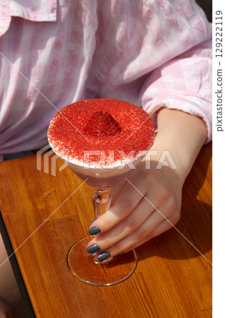 Woman holding a glass with a delicious dessert topped with freeze-dried strawberries and red velvet powder Woman holding a glass with a delicious dessert topped with freeze-dried strawberries and red velvet powder 129222119