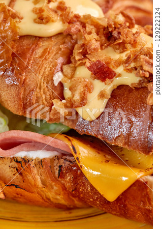 Delicious croissant sandwich dripping with melted cheddar cheese and crispy fried onions Delicious croissant sandwich dripping with melted cheddar cheese and crispy fried onions 129222124