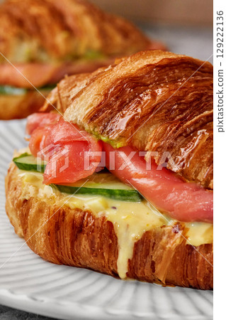 Delicious croissant sandwich featuring smoked salmon, cucumber, and creamy sauce Delicious croissant sandwich featuring smoked salmon, cucumber, and creamy sauce 129222136