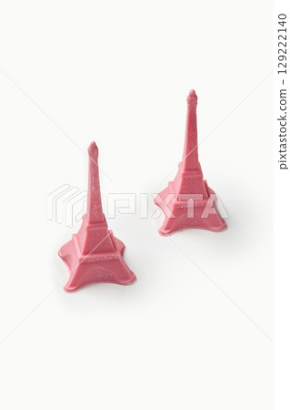 Two pink eiffel tower statues resting on white background Two pink eiffel tower statues resting on white background 129222140