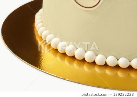 Delicious round cake decorated with white sugar pearls on golden cardboard base Delicious round cake decorated with white sugar pearls on golden cardboard base 129222228