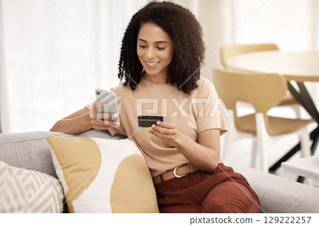 Black woman, smartphone and credit card on sofa for ecommerce, online banking and paying bills in living room. African American female, young lady or cellphone for connection, payment query and smile 129222257