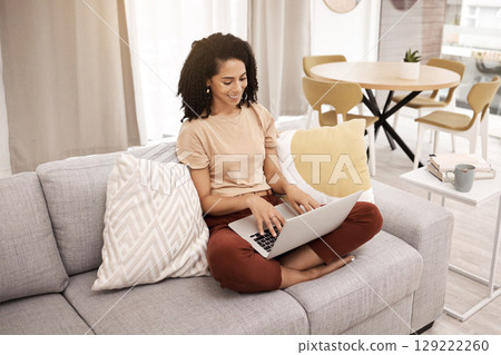 Black woman, working and home laptop typing in living room happy about writing planner. Technology, living room and computer research of a digital worker doing remote work for online freelancer job Black woman, working and home laptop typing in living room happy about writing planner. Technology, living room and computer research of a digital worker doing remote work for online freelancer job 129222260