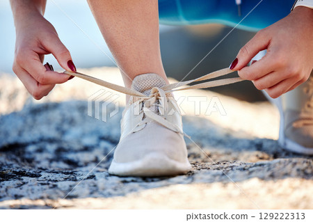 Shoes, running and fitness with a sports woman tying her laces before a cardio or endurance run outdoor. Road, health and exercise with a female runner fastening her shoelaces before a workout 129222313