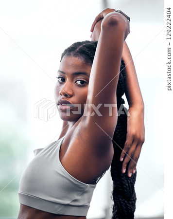 Workout, portrait and black woman stretching arm for self care, wellness and health at club. Exercise, training and athlete warm up in gym for body cardio with serious and determined face. 129222404