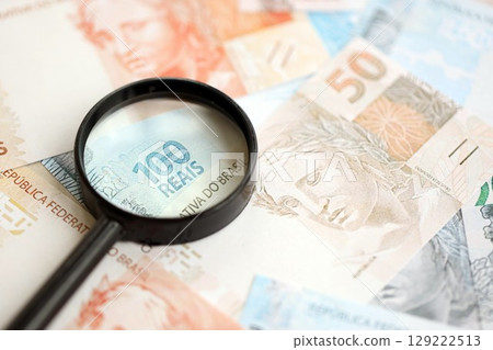 Brazilian reais banknotes and magnifying glass. The current Brazil real money bills and loupe 129222513