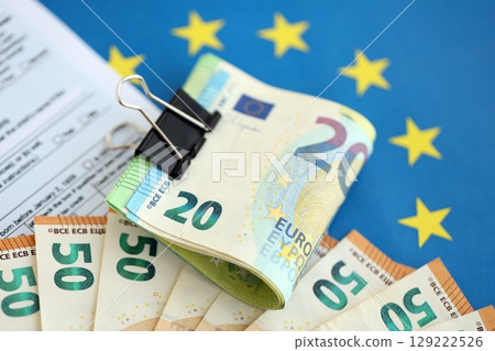 European euro currency money notes bunch on tax form and European union blue flag close up 129222526