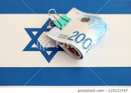 Israel New Shekels banknotes on national flag. The current Israel money bills lies on flag in big amount 129222547