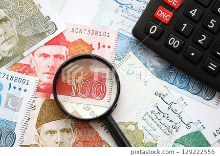 Pakistan rupees banknotes and calculator with magnifying glass. Pakistan money bills calc with loupe 129222556