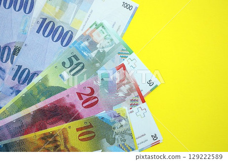 Swiss franc banknotes on yellow. The current francs money bills lies on table in big amount Swiss franc banknotes on yellow. The current francs money bills lies on table in big amount 129222589
