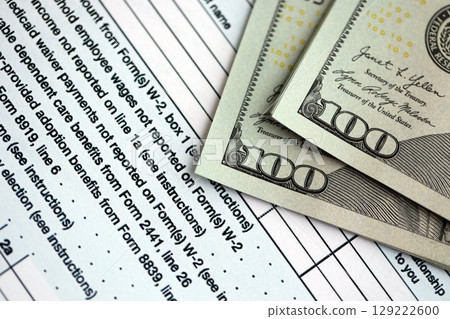 Hundred dollar bills and 1040 individual income tax return form blank close up 129222600