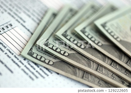 Big amount of United States dollar bills on table with 1040 tax return form 129222605