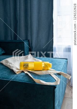 Yellow water bottle on beige eco shopper bag. 129222628