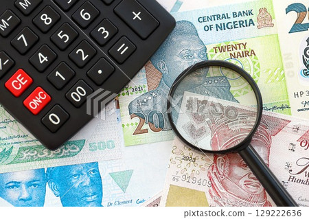 Nigerian naira currency money bills and calculator with magnifying glass. The concept of taxation and money count 129222636