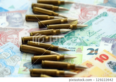 Nigerian naira currency money bills and rifle bullets. The concept of warfare and gun selling 129222642