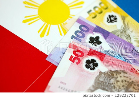 Philippines peso currency money bills lies on flag. The concept of business and investment Philippines peso currency money bills lies on flag. The concept of business and investment 129222701