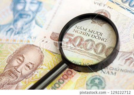Vietnamese dong currency money bills and magnifying glass. The concept of financial monitoring and taxation Vietnamese dong currency money bills and magnifying glass. The concept of financial monitoring and taxation 129222712
