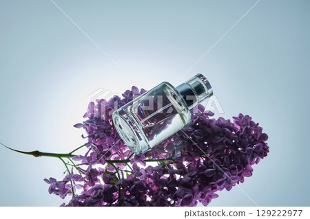 A bottle of perfume on a lilac branch in close-up. 129222977