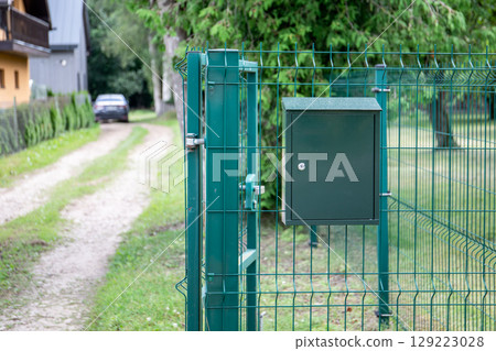 Green Mailbox Mounted on Metal Fence by Country Road 129223028
