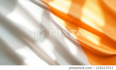 Gentle light casting shadows on orange and white fabric 129223551