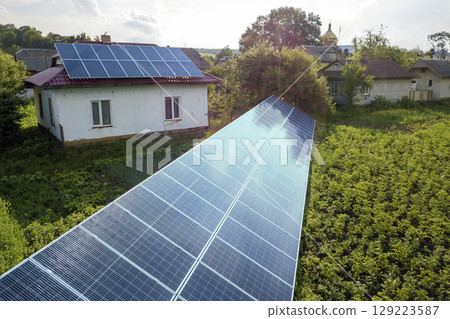 Aerial view of a house with blue solar panels for clean energy. Aerial view of a house with blue solar panels for clean energy. 129223587