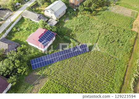 Aerial view of a house with blue solar panels for clean energy. 129223594