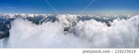 Aerial view from airplane window at high altitude of earth covered with puffy cumulus clouds forming before rainstorm. Aerial view from airplane window at high altitude of earth covered with puffy cumulus clouds forming before rainstorm. 129223614