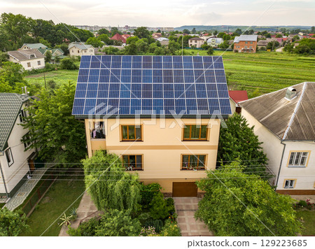 Aerial top view of new modern residential house cottage with blue shiny solar photo voltaic panels system on roof. Renewable ecological green energy production concept. 129223685