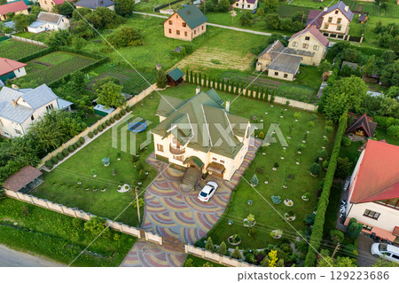 Aerial top view of house shingle roof and a car on paved yard with green grass lawn. 129223686