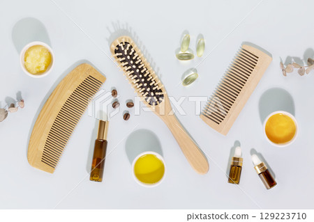 Hair care flat lay with wooden combs, ingredients for mask for hair, vitamins for health hair and natural oils on a blue background. Natural beauty products for health hair 129223710