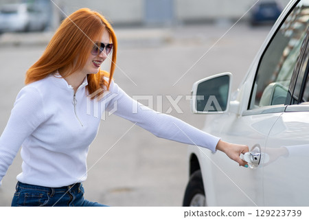 A woman trying to open closed car doors. A woman trying to open closed car doors. 129223739