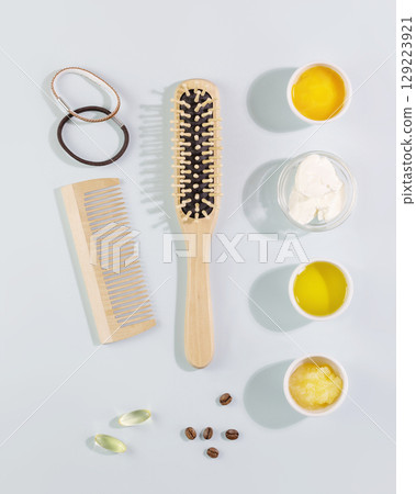 Hair care flat lay with wooden combs, ingredients for mask for hair, vitamins for health hair on a blue background. Natural beauty products for hair 129223921
