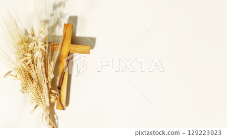 Wooden crucifixion with bouquet of wheat and rye on light background with copy space. Religion background suitable for faith religion, christian holidays, Easter, Redeemer, the Feast of Corpus Christi 129223923