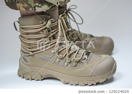 Detailed close up of military soldier s high lace up boots on plain white backdrop 129224020