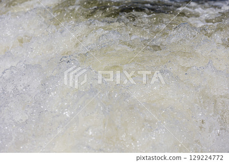 Turbulent water, showing churning foam, bubbles, and surface tension. 129224772