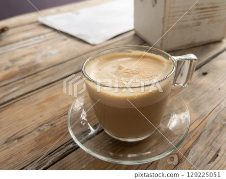 Glass cup of coffee on rustic wooden table in outdoor cafe Glass cup of coffee on rustic wooden table in outdoor cafe 129225051