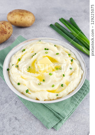 Mashed potatoes with melted butter and chopped green onions on a gray background. Irish mashed potatoes champ. Mashed potatoes with melted butter and chopped green onions on a gray background. Irish mashed potatoes champ. 129225075
