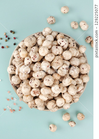 Bowl of makhana, fox nut or lotus seeds rich in protein with salt and pepper on blue background. Top view. Close up. Indian food. 129225077