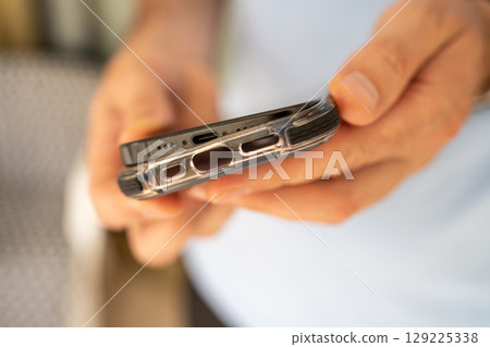 Close-up of a man putting on a protective shockproof case on his phone. 129225338