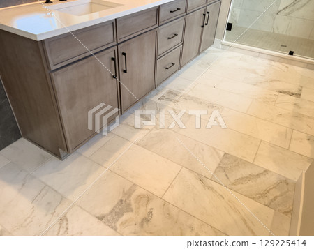 Bright modern bathroom interior featuring light marble tile flooring, sleek wood cabinets with black handles, and a glass shower enclosure. Ideal for real estate listings, renovation concepts, or Bright modern bathroom interior featuring light marble tile flooring, sleek wood cabinets with black handles, and a glass shower enclosure. Ideal for real estate listings, renovation concepts, or 129225414