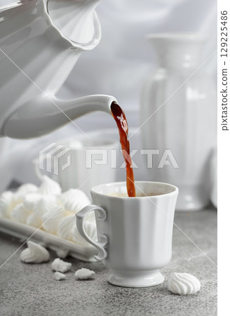 Black coffee in white porcelain cup and white small French meringues. Black coffee in white porcelain cup and white small French meringues. 129225486