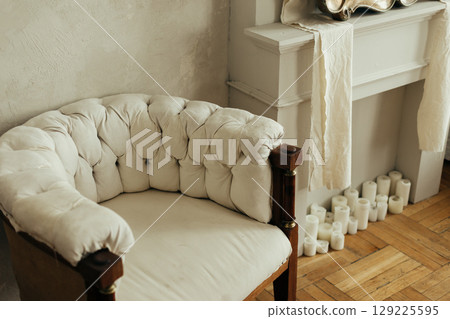 Classical style living room interior with fluffy armchair with wooden legs and decorative chimney 129225595