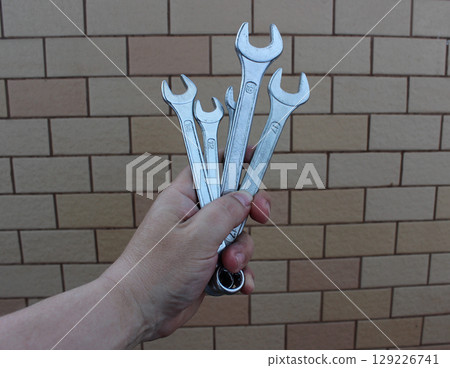 Different Size Steel Hex Wrenches In A Human Hand On A Bricks Background Different Size Steel Hex Wrenches In A Human Hand On A Bricks Background 129226741