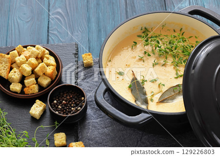 creamy salmon soup with herb in a pot 129226803