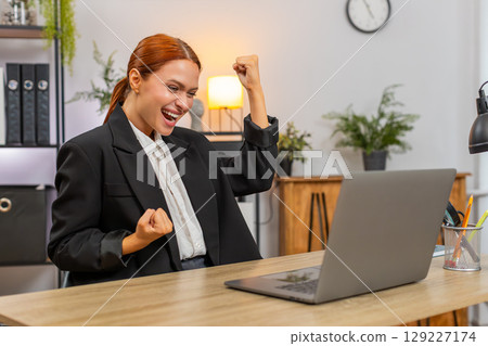 Young businesswoman celebrates project approval on laptop breathes loudly shouting victory success Young businesswoman celebrates project approval on laptop breathes loudly shouting victory success 129227174