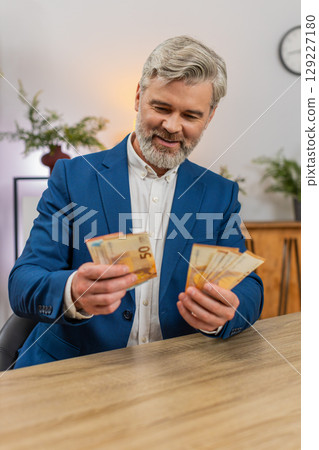 Middle-aged businessman holding euro cash counting salary income celebrating big success happiness 129227180