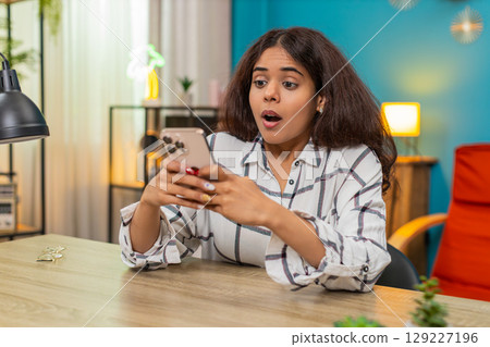 Indian woman celebrates victory after news on smartphone raising fist smiling joyful success message 129227196