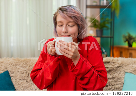 Woman enjoying drinking coffee sitting comfortably on sofa relaxed satisfied calm leisure expression 129227213